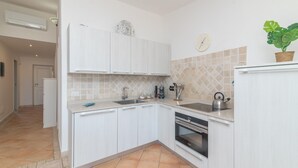 A modern kitchen with white cabinets, a stainless steel sink, and an oven. - Feel So Good in Bunthe (Olbia)