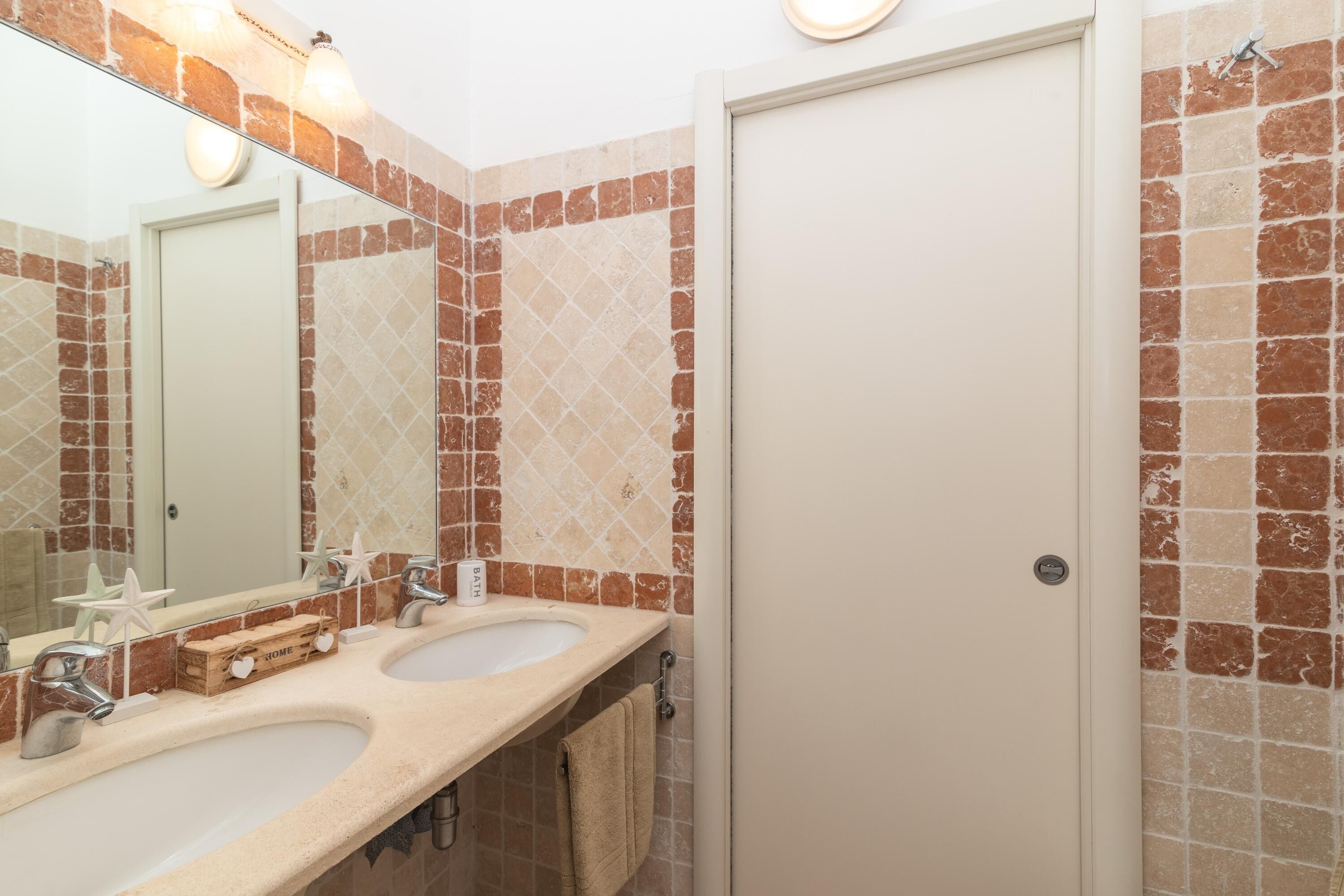 Un baño con dos lavamanos, un espejo y una puerta.