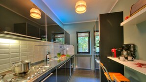 Une cuisine moderne dotée d’appareils électroménagers en acier inoxydable, d’un long plan de travail et d’une fenêtre laissant entrer la lumière naturelle.