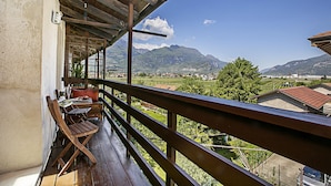 Un balcón de madera con vistas a montañas y un viñedo.