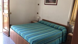 Un dormitorio con cama, una mesita de noche, una lámpara y dos cuadros en la pared.