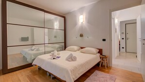 Une chambre à coucher avec un lit, un plancher en bois, un miroir et une table de chevet.