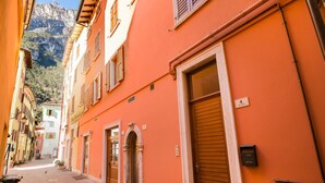 A narrow street with buildings on either side, a closed shop door, and a mountain in the background. - Ca Cerere in Riva del Garda (Riva del Garda)