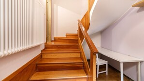 A wooden staircase with a white chair and a white table in a room with light-colored walls and a radiator. - Ca Cerere in Riva del Garda (Riva del Garda)