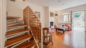 Eine Treppe mit Holzboden und Holzhandlauf, die zu einem Wohnzimmer mit Sofa, Couchtisch und Kamin führt.