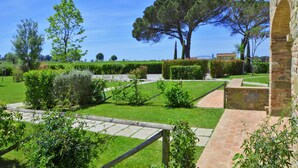 A well-maintained garden with a stone pathway, neatly trimmed hedges, and a large tree. - Fratta Ginestre in Cortona (Cortona)