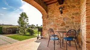 An outdoor patio with stone walls, a table, and chairs. - Fratta Ginestre in Cortona (Cortona)