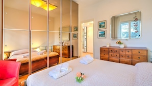 A hotel room with a large bed, a red chair, a wooden dresser, and a mirror. - Gabri By The Sea in Diano Marina (Diano Marina)