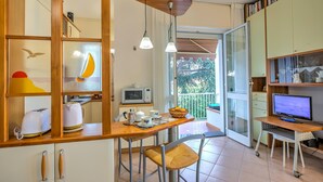 A compact kitchen with a wooden countertop, a microwave, a toaster, and a dining area with a chair. - Gabri By The Sea in Diano Marina (Diano Marina)