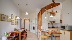 A modern kitchen with wooden cabinets, a dining area with a table set for four, and a bar area with stools. - Gabri By The Sea in Diano Marina (Diano Marina)