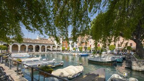 Un port de plaisance avec des bateaux amarrés, un bateau à couvert et un bâtiment avec des arches en arrière-plan.