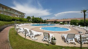 Une zone avec piscine, des chaises longues et un bâtiment en arrière-plan.
