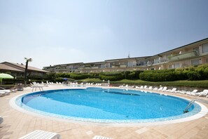 A swimming pool surrounded by lounge chairs and a building with balconies. - Casa Kristall Lago in Desenzano del Garda (Desenzano del Garda)