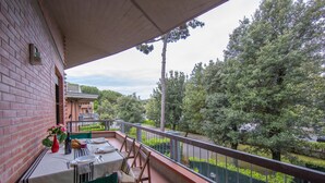 Een balkon met een eettafel, een bloevas en uitzicht op een groen landschap.
