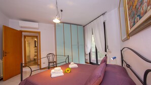 Een slaapkamer met een bed, een stoel, een bureau en een raam met gordijnen.