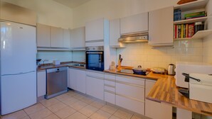A modern kitchen with white cabinets, a built-in oven, a dishwasher, and a wooden countertop. - Blooming Villa Cos in Belgirate (Belgirate)