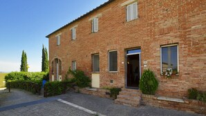 Un bâtiment à deux étages, construit en briques, avec une entrée pavée et un petit jardin.