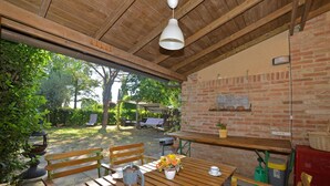 Une terrasse extérieure avec des meubles en bois, un mur en briques et un luminaire suspendu.