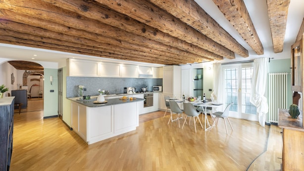 Une cuisine moderne avec des poutres en bois, un îlot central et un coin repas avec des chaises.