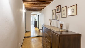 Un couloir avec un plancher en bois, une armoire en bois et des tableaux encadrés accrochés au mur.