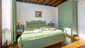 A bedroom with a bed, a nightstand, a dresser, and a window with curtains. - Mimosa in Hilly Area (Gargnano)