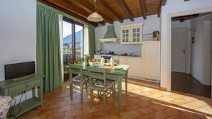 A dining area with a wooden ceiling, a table set for two, and a view of mountains through a window. - Mimosa in Hilly Area (Gargnano)