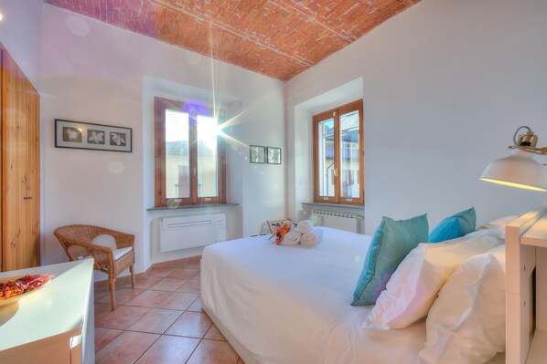 Een slaapkamer met een groot bed, een stoel en een tafel met een dienblad eten.