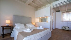 A neatly arranged bedroom with a large bed, bedside tables, a mirror, and an air conditioning unit. - Il Bacco few Steps From sea (Camaiore)