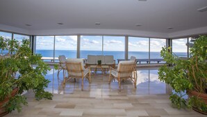 A spacious room with a large view of the sea, a central table with chairs, and potted plants. - Il Suono del Mare 200 mt From sea (Cervo)