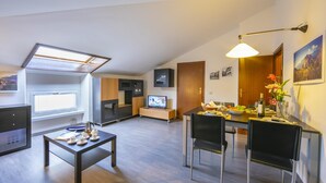 Un appartamento moderno con zona pranzo, cucina e TV.