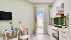 Una cuina compacta amb zona de menjador, un televisor penjat a la paret i una porta corredissa de vidre que dona a una zona exterior.