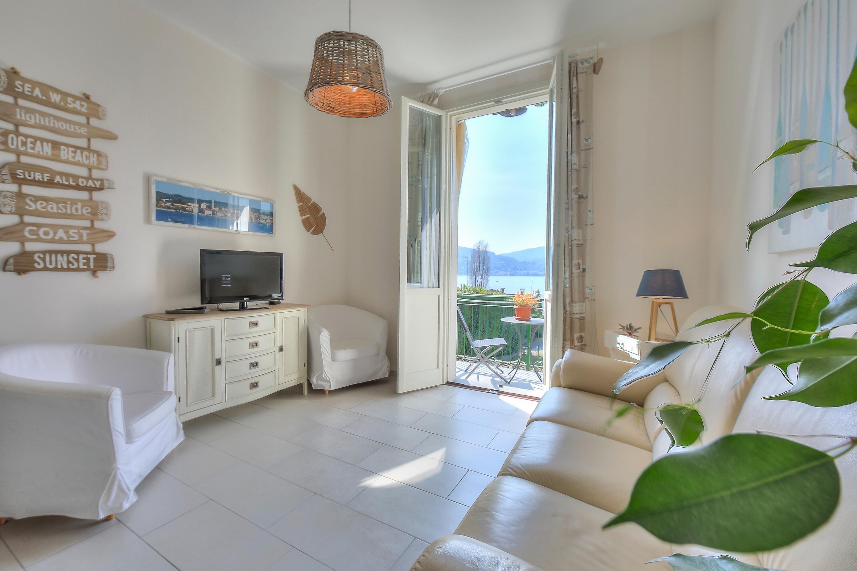 A living room with a sofa, TV, and a view of the sea.