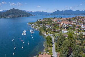 An aerial view of a lakeside town with residential buildings, a marina with boats, and mountains in the background. - La Casa Sul Lago Maggiore (Ranco)