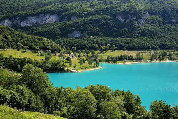A coastal landscape with a clear turquoise lake, lush greenery, and a cliffside.