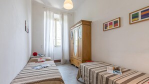 Una habitación con dos camas, un armario de madera y una ventana con cortinas.