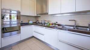 Een moderne keuken met roestvrijstalen apparatuur, witte kasten en een groot keukenblok met een spoelbak.