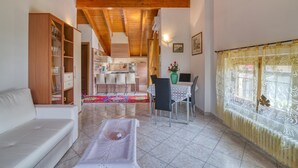 A spacious living area with a wooden ceiling, a dining table with chairs, a sofa, and a cabinet with glass doors. - Casa Maddalena Private Beach Upon Reques (Cadrezzate con Osmate)