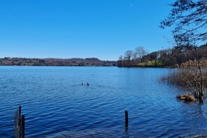 A calm lake with a clear sky, surrounded by trees and a distant shoreline. - Casa Maddalena Private Beach Upon Reques (Cadrezzate con Osmate)