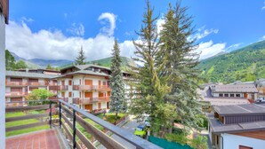 Un quartier résidentiel comprenant plusieurs immeubles, un balcon et une vue sur une montagne.