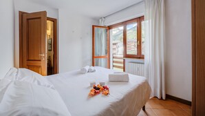 Une chambre d’hôtel avec un lit, une fenêtre avec des rideaux, une porte et une vue sur l’extérieur.