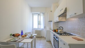 A compact kitchen with white cabinets, a gas stove, and a window providing natural light. - Casa Al Caprifoglio in Ispra (Ispra)