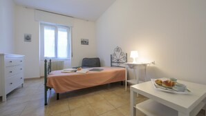 A bedroom with a bed, a bedside table with a lamp, a dresser, and a window. - Casa Al Caprifoglio in Ispra (Ispra)