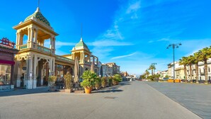 Ένας δρόμος με ένα κτίριο που διαθέτει έναν πράσινο θόλο και κολόνες.
