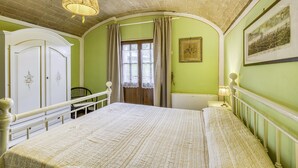 A bedroom with a large bed, a wardrobe, a chair, and a window with curtains. - Maramaldo Morellino Shared Pool Chianti (Castelfiorentino)