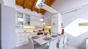 A modern kitchen with white cabinetry, a dining table set for four, and a skylight above. - Blu Lake Apartment on Ghiffa Beach (Ghiffa)