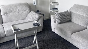 A modern living room with two grey sofas, a white coffee table, a floor lamp, and a white shelving unit with books and decorative items. - 2 Bed Flat - Sleeps 4 - Pets - Parking - Wifi (Edinburgh)