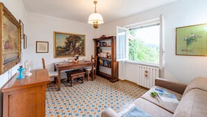 A cozy room with a wooden desk, a bookshelf, a dining table, and a sofa. - Il Cortiletto di Marina (Brovello-Carpugnino)