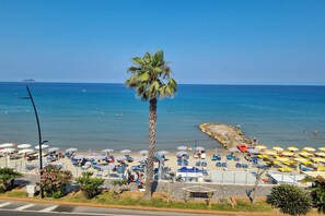 A beach with palm trees, umbrellas, and lounge chairs. - Laigueglia Beach in Laigueglia (Laigueglia)
