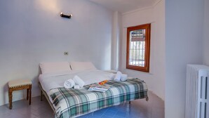 A bedroom with a bed, a small wooden stool, a window, and a radiator. - Appartamento Zia Anna Ski in Ski out (Sauze d'Oulx)