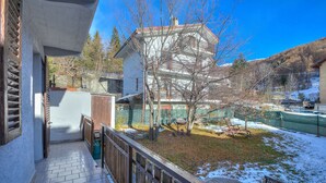 A wooden balcony with a view of a snow-covered yard and a two-story building with a balcony. - Appartamento Zia Anna Ski in Ski out (Sauze d'Oulx)